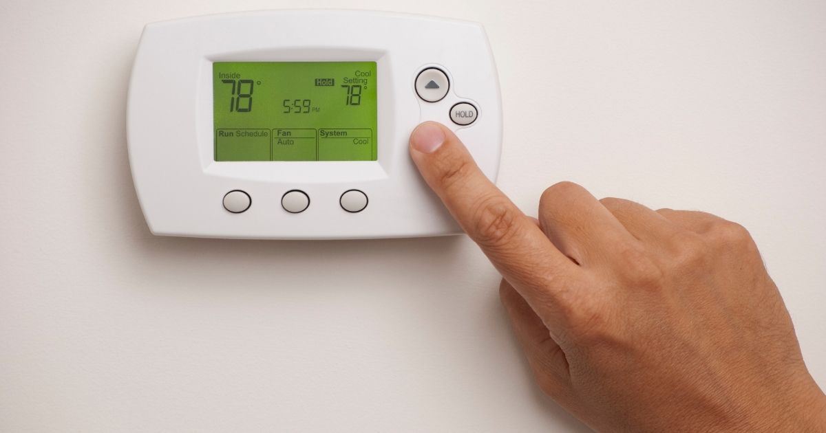 Thermostat and a hand using the keypad